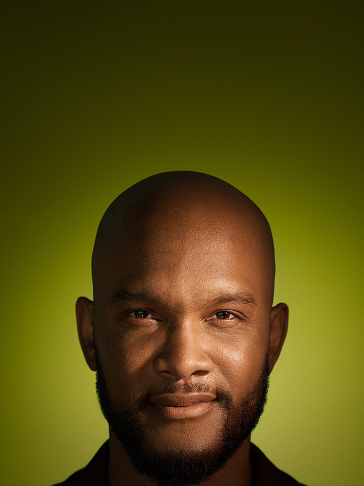 Portrait of a bald Black man with a beard on a green background