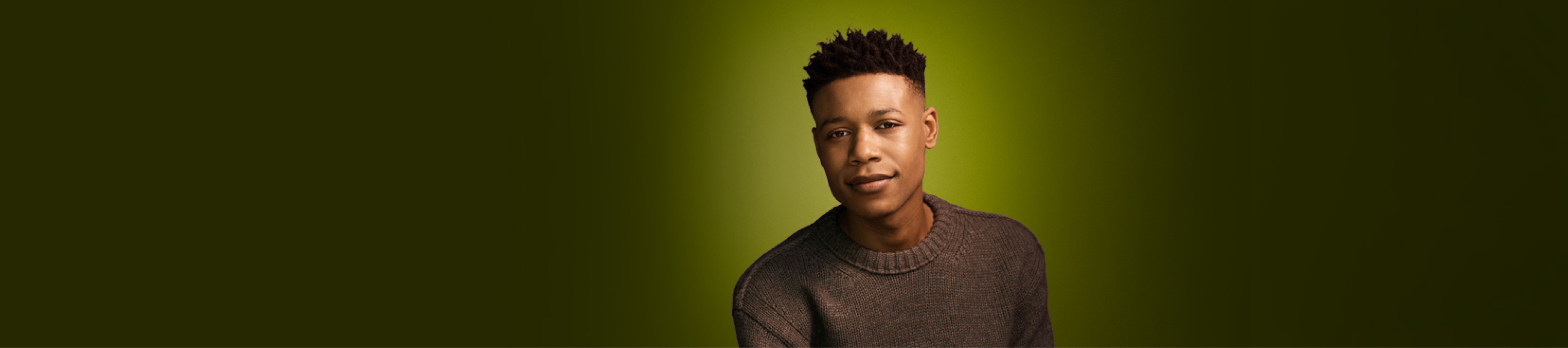 Portrait of a young Black male wearing a brown sweater.